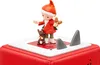 A close-up shot of a red Toniebox with a white top, featuring a figurine of a gnome-like character with a squirrel and shark fins. Produktbild-Vorschau