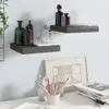Two floating shelves are mounted on a light gray wall, displaying various decorative items and books. Below the shelves, a white desk holds a framed artwork, a vase, and a cup filled with pens and pencils. A stack of magazines is also visible on the desk. Anteprima dell’immagine prodotto