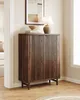 A dark wood cabinet with slatted doors stands in a room, topped with a lamp and decorative items. Náhľad obrázku produktu