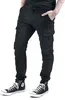 A person wearing black cargo jogging pants and black high-top sneakers, shown from the waist down against a white background. Anteprima dell’immagine prodotto