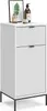 A white cabinet with a fluted door and drawer, standing on black legs, is shown against a white background. Decorative items are placed on top of the cabinet. Náhled obrázku produktu