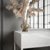A close-up of a white vanity table with a glass vase containing dried reeds. Náhled obrázku produktu