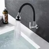 A black flexible kitchen faucet is mounted on a gray tiled wall, spraying water into a white sink filled with water. Náhľad obrázku produktu