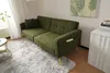 A green sofa is displayed in a room with a fluffy rug and a side table. Produktbild-Vorschau