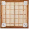 A top-down view of a carrom board with a wooden frame and a grid of wooden dividers on a light-colored surface. Four white mesh bags are placed at the corners. Náhled obrázku produktu