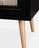 A close-up view of the bottom corner of a black bedside table with a cane detail, showing its wooden legs. Anteprima dell’immagine prodotto