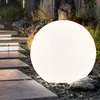 A large, illuminated spherical lamp sits on a gravel path next to a stone staircase in a garden. Produktbild-Vorschau
