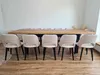A dining set with a long wooden table and multiple chairs arranged around it in a room with white walls and wooden flooring. Produktbild-Vorschau