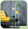A yellow armchair is placed next to a modern white plant stand with several potted plants. Anteprima dell’immagine prodotto