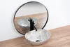 A marble sink with a black faucet is placed on a wooden countertop, with a round mirror reflecting the scene. Podgląd zdjęcia produktu