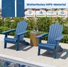 Two blue Adirondack chairs are placed on a patio next to a pool, with a small wooden table between them. The background shows a stone wall and greenery. Produktbild-Vorschau