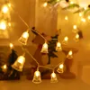 A string of bell-shaped Christmas lights with a blurred background of Christmas decorations. Náhled obrázku produktu