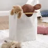 A white laundry basket filled with stuffed animals sits on a fluffy white rug. Náhľad obrázku produktu