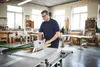A man is using a table saw in a workshop. Podgląd zdjęcia produktu