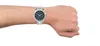 A man's arm wearing a silver watch with a black face. Voir les images du produit