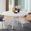A round white dining table with a vase of flowers and a bottle of wine on it, set in a dining room with chairs and curtains. Náhled obrázku produktu