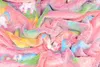 A close-up view of a soft, fluffy blanket with a rainbow tie-dye pattern and unicorn prints. Anteprima dell’immagine prodotto