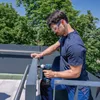 A man is using a Bosch cordless impact wrench to attach a railing on a balcony. Voir les images du produit