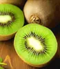 A close-up view of two halves of a kiwi fruit, revealing its vibrant green flesh and black seeds, with a whole kiwi in the background. Produktbild-Vorschau