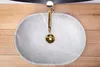 A top-down view of a beige oval sink with a gold faucet. Náhled obrázku produktu