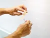 Hands holding a strip of beige medical tape. Anteprima dell’immagine prodotto