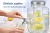 A hand is pouring water from a glass beverage dispenser into a glass. Produktbild-Vorschau
