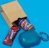 A brown paper bag with a jar of peanut butter and a candy bar peeking out, next to a teal earbud case. Anteprima dell’immagine prodotto