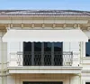 A beige awning is installed above a balcony on a building. Voir les images du produit
