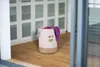 A pink laundry basket with a giraffe design sits on a wooden floor in front of a white cabinet. Produktbild-Vorschau