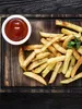 A close-up overhead view of french fries and ketchup on a wooden board. Produktbild-Vorschau