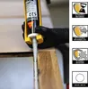 A hand wearing a black glove is using a caulking gun to apply white sealant to a wooden joint. Voir les images du produit