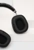 A close-up shot of black wireless headphones on a white and light gray surface. Produktbild-Vorschau