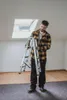 A man is holding a folded aluminum ladder indoors, with a skylight in the background. Produktbild-Vorschau