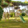 A wooden playground set with a slide, swings, and climbing net is set up on a grassy lawn surrounded by trees. Náhľad obrázku produktu