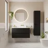 A modern bathroom with a black vanity, a round illuminated mirror, and a tall black cabinet. Voir les images du produit