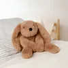 A plush toy bunny sitting on a bed. Voir les images du produit