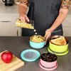 A person is pouring food into a set of stainless steel and silicone food containers on a kitchen counter. Produktbild-Vorschau
