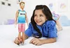 A young girl is lying on a bed, holding a Ken doll. Produktbild-Vorschau