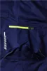 A close-up view of a dark blue work pant pocket with a yellow zipper and reflective detailing. Produktbild-Vorschau