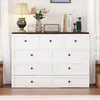 A white dresser with a dark brown top is shown in a room with soft lighting. Decorative items are placed on top of the dresser. Produktbild-Vorschau