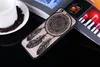 A phone case with a dreamcatcher design is placed on a table next to a cup of coffee and some books.