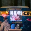 People watching a movie outdoors at night, with two Bluetooth speakers in the foreground. Produktbild-Vorschau