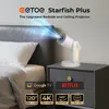 A projector is placed on a nightstand next to a bed, projecting a blue light beam. Produktbild-Vorschau
