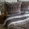 A close-up view of a bedding set with a patterned pillow and duvet cover. Produktbild-Vorschau