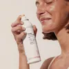 A woman is spraying a mist onto her face. Produktbild-Vorschau