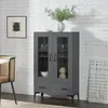 A dark gray display cabinet with glass doors and drawers, placed against a white brick wall. Náhľad obrázku produktu