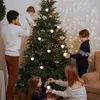 A family is decorating a Christmas tree indoors. Produktbild-Vorschau