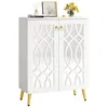 A white shoe cabinet with mirrored doors and gold legs, decorated with a framed picture, a vase of yellow flowers, and books on top. Produktbild-Vorschau