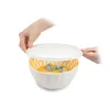 Hands placing a lid on a bowl of soup with broccoli. Náhľad obrázku produktu