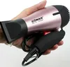 A hand holding a pink and black hairdryer. Produktbild-Vorschau